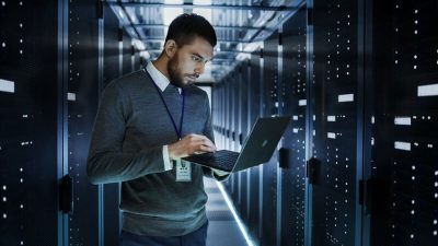 Man working on laptop in server room